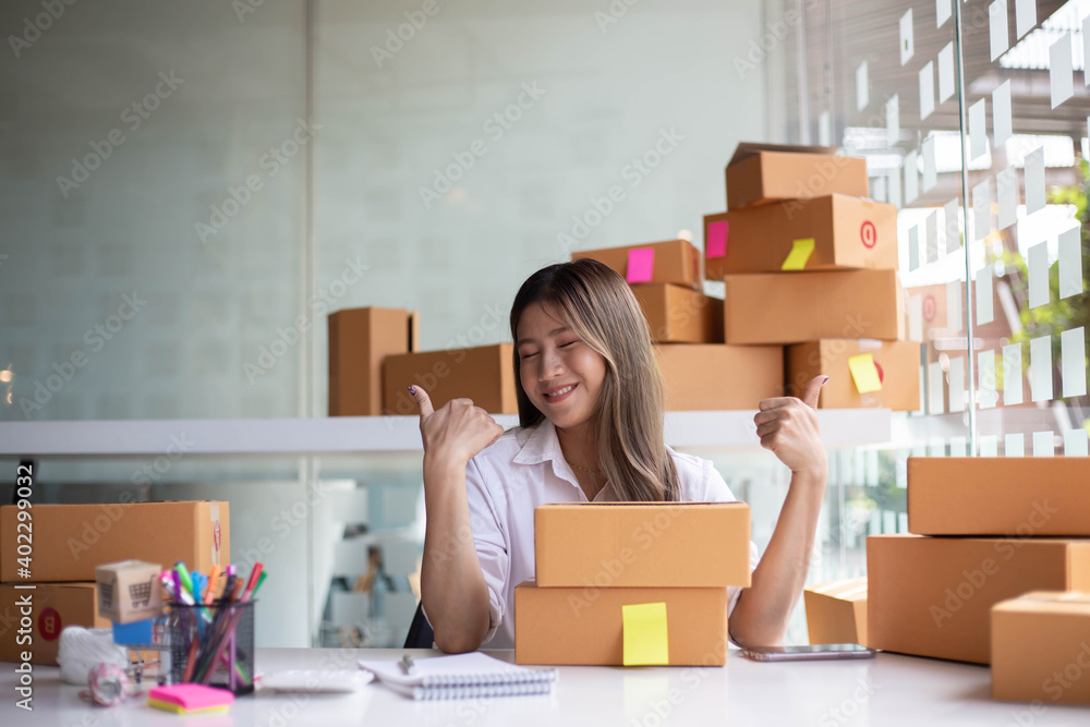 An Asian owner holds a package in a brown box, ready for delivery to a customer who orders online. A