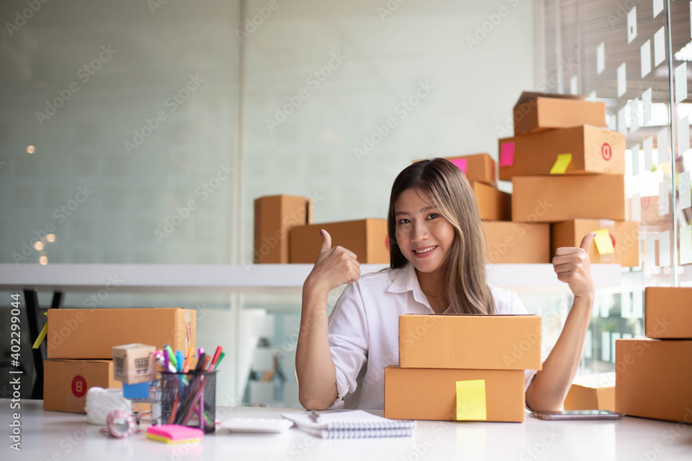 An Asian owner holds a package in a brown box, ready for delivery to a customer who orders online. A