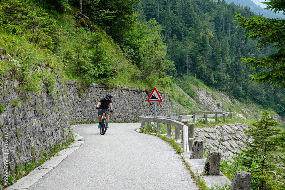 一名男性游客在斯洛文尼亚山区的一条陡峭道路上骑着电动自行车。