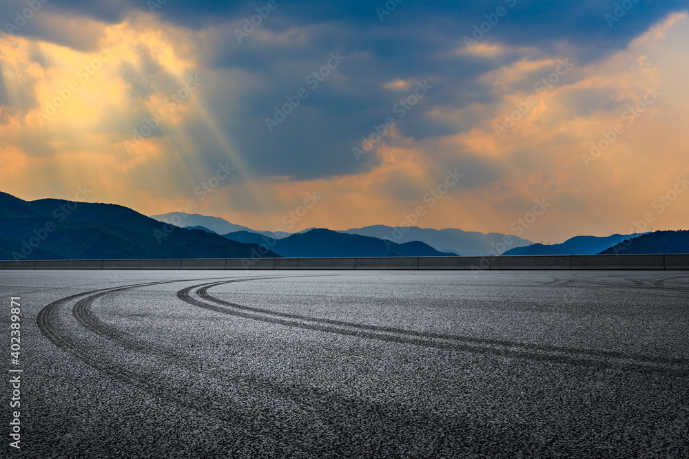 日落时的沥青路面和山脉。赛道道路和山脉背景。