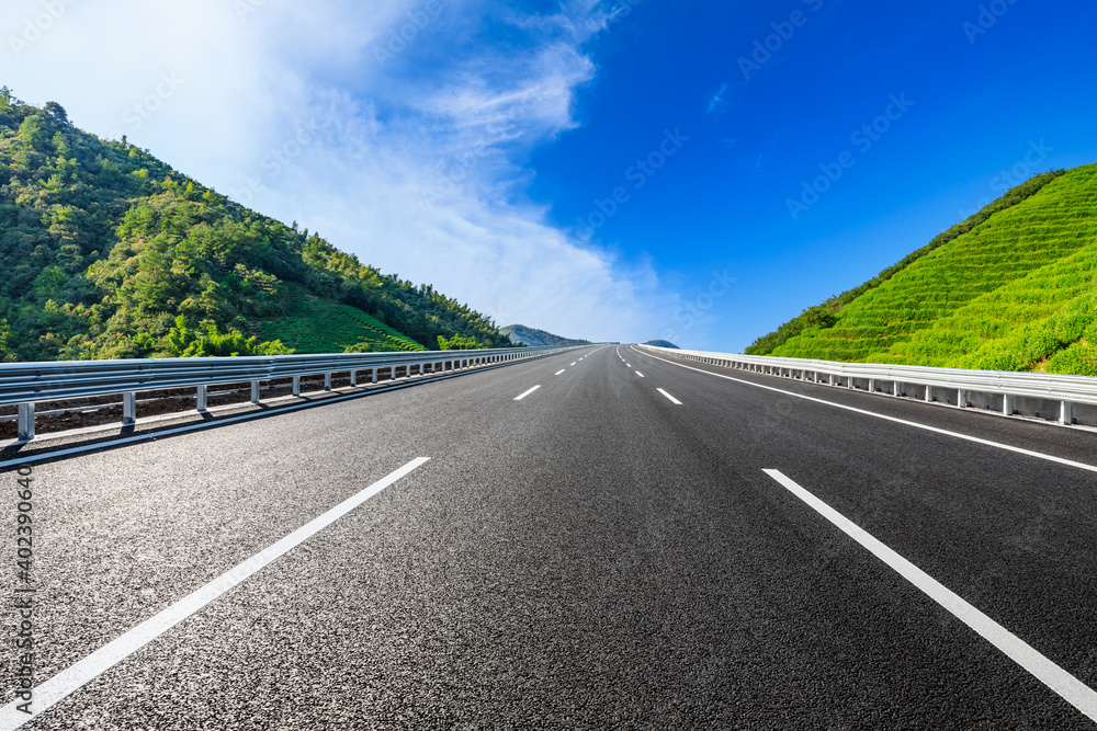 Asphalt road and mountain with tea plantation under blue sky.Road and mountain background.