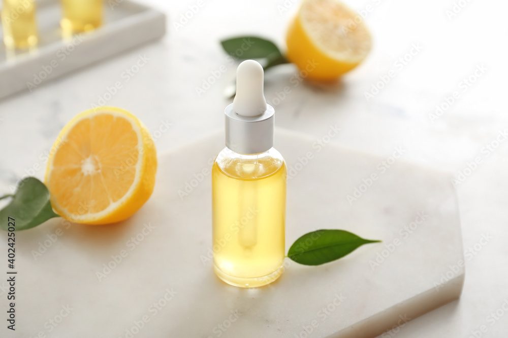 Bottle with lemon essential oil on light background