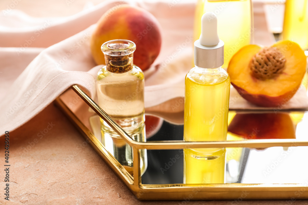 Bottles with peach essential oil on table