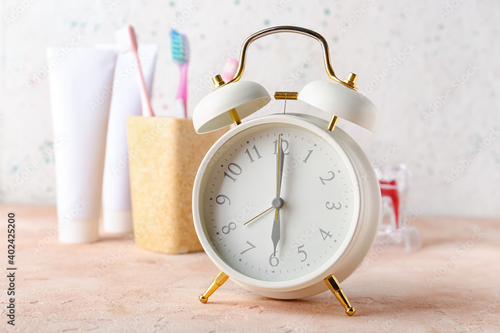 Alarm clock and set of oral care products on table