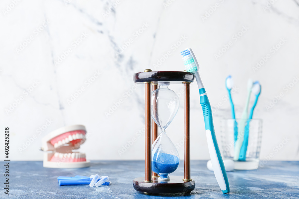 Hourglass, model of jaw and toothbrushes on table