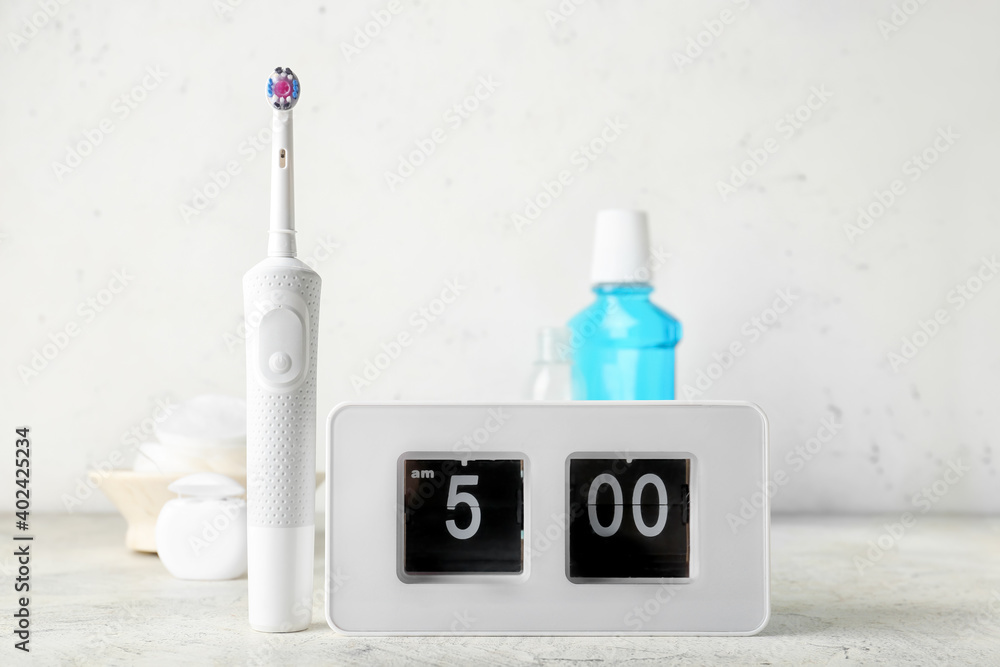 Alarm clock and set of oral care products on table