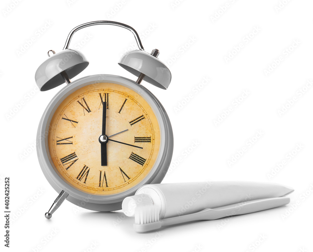 Alarm clock, paste and toothbrush on white background