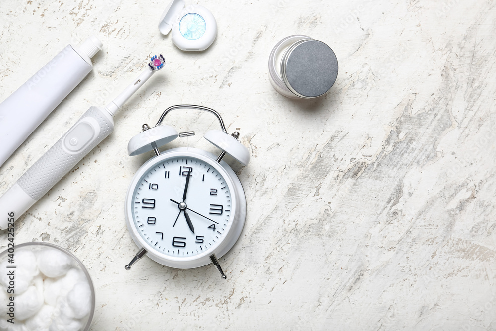 Alarm clock and set of oral care products on light background