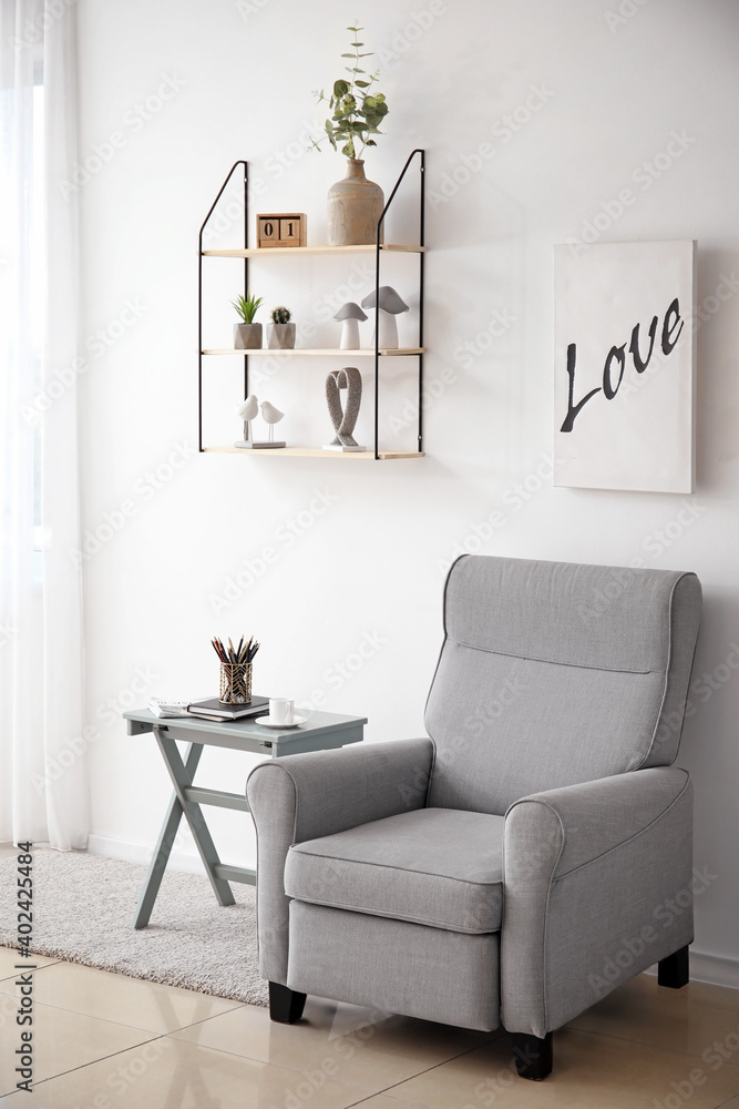 Soft armchair, table and shelf in interior of living room