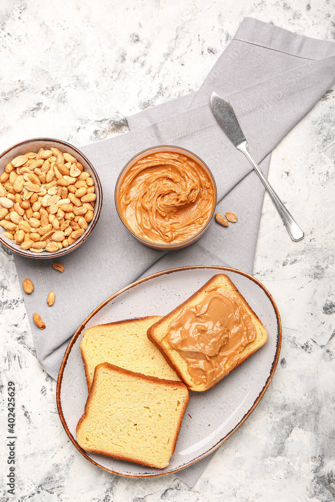 Bowl with tasty peanut butter, toasts and nuts on table