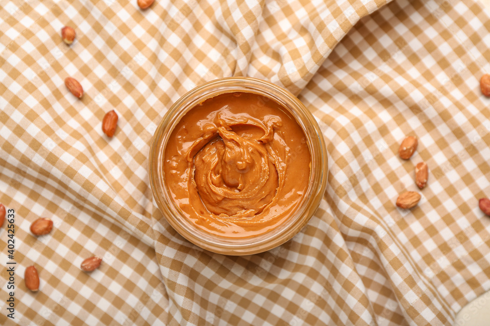 Bowl with tasty peanut butter on fabric background