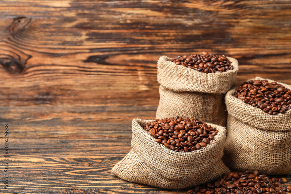 Bags with coffee beans on wooden background