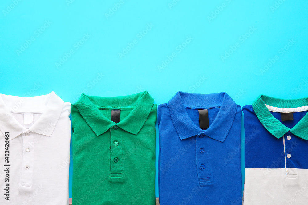 Folded polo shirts on color background