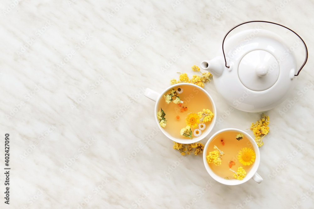 Teapot and cups with floral tea on light background