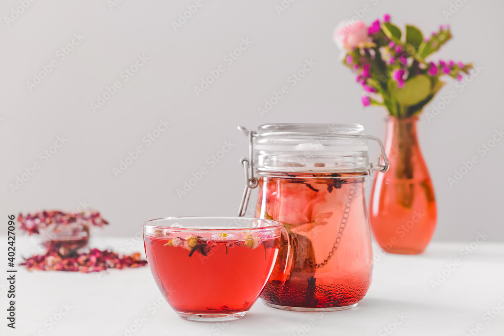 Flowers in vase, teapot and cup with floral tea on light background