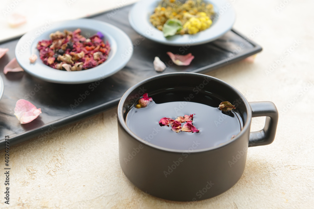 Cup with floral tea and dry flowers on light background