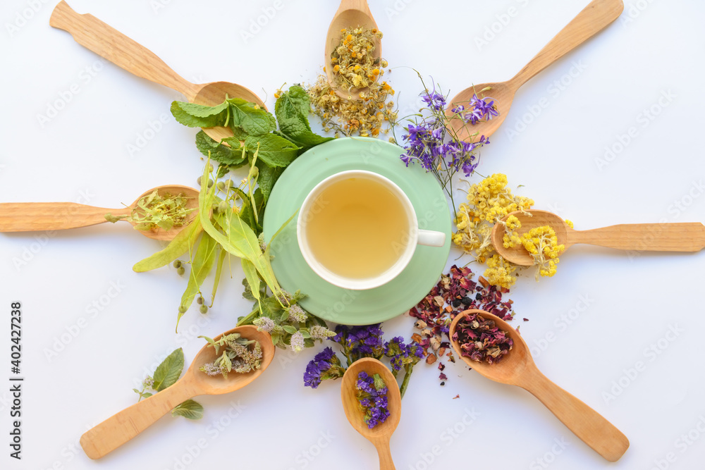 Dry flowers, spoons and cup with floral tea on light background