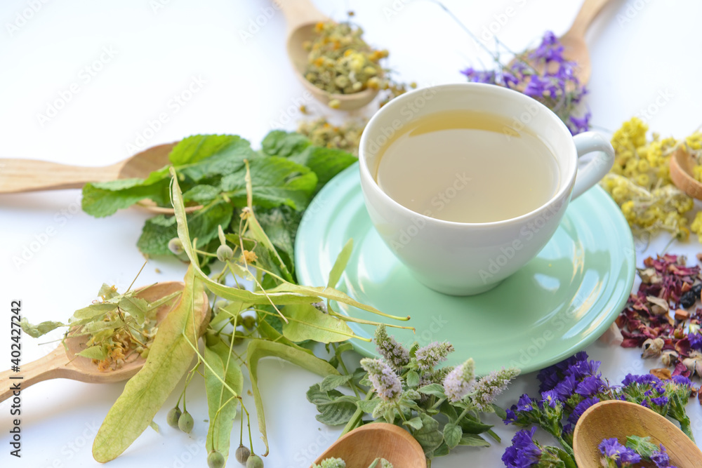 Dry flowers, spoons and cup with floral tea on light background