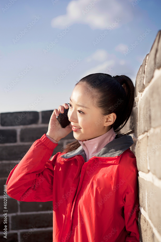 一名年轻女子在长城旅游中使用手机