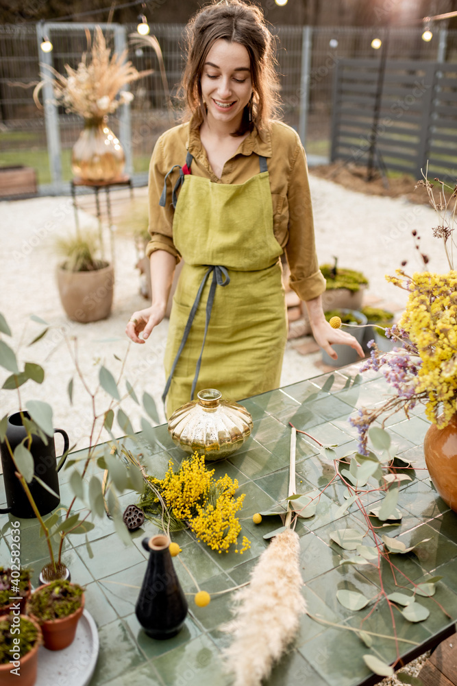 年轻女子在户外工作室制作干花、鲜花和香草的组合物。Flori