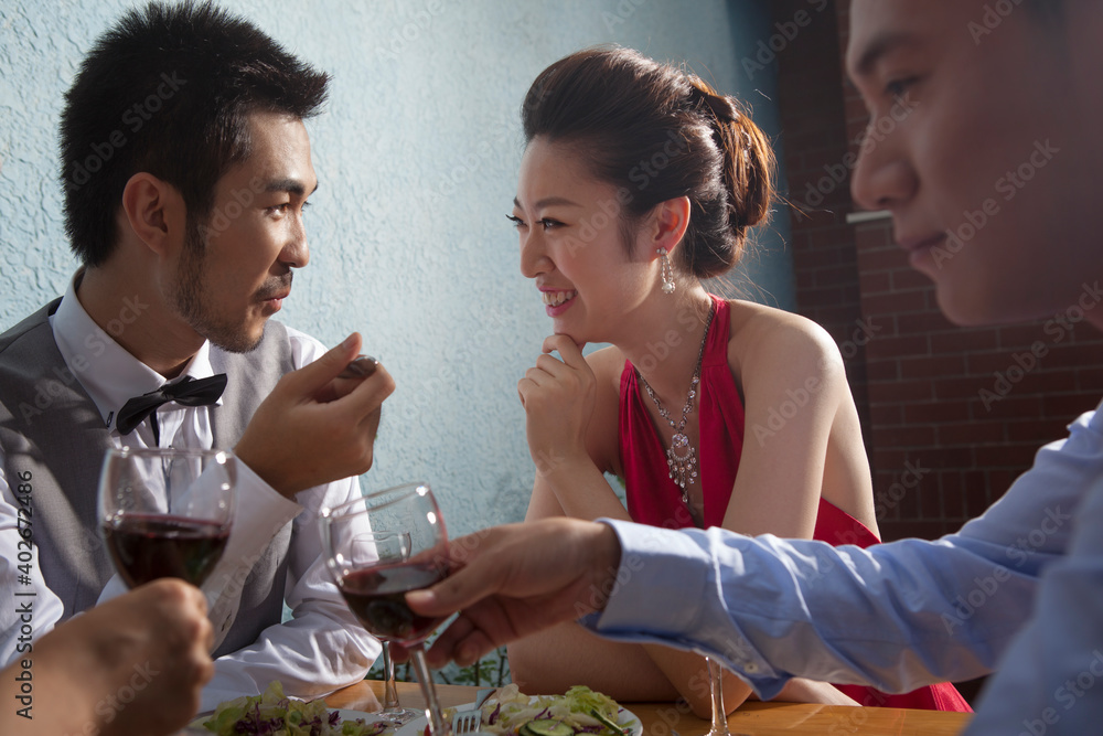 Four people sit together for dinner and chat 