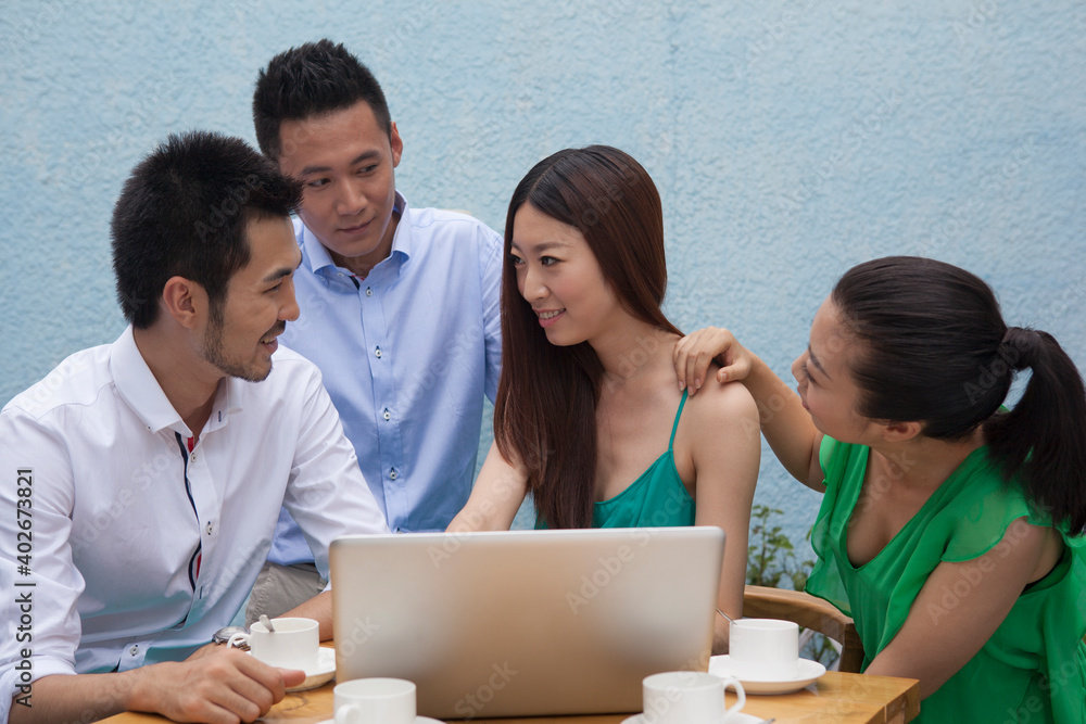 Four people sit together working with computers 