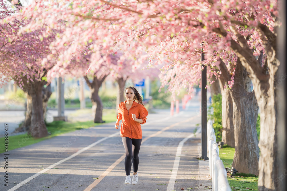 亚洲女性早上锻炼她在樱花公园跑步。