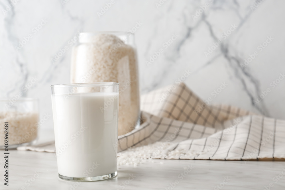 Glass with tasty rice milk on table