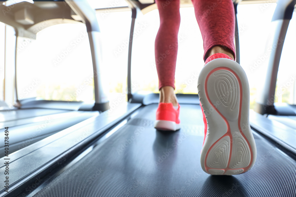 Woman training on treadmill in gym, closeup