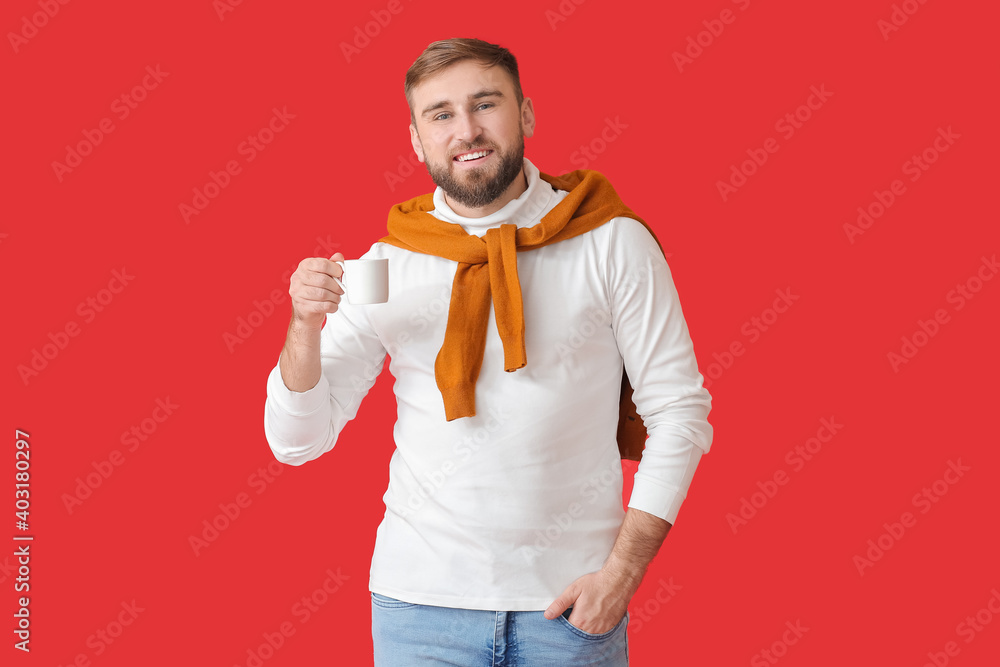 Handsome young man with hot coffee on color background