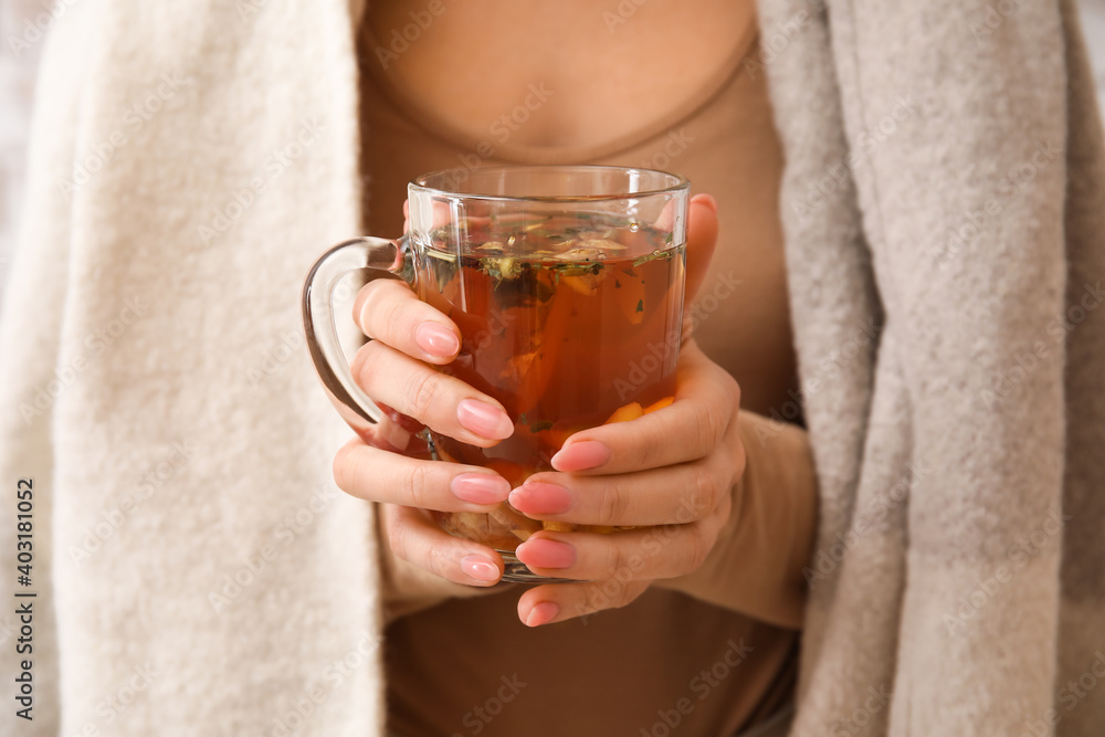 Woman holding cup of hot ginger tea, closeup