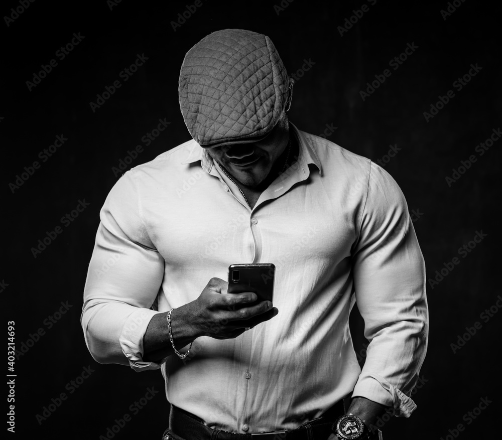 Black and white portrait of stylish unrecognizible african american with head down looking at phone.