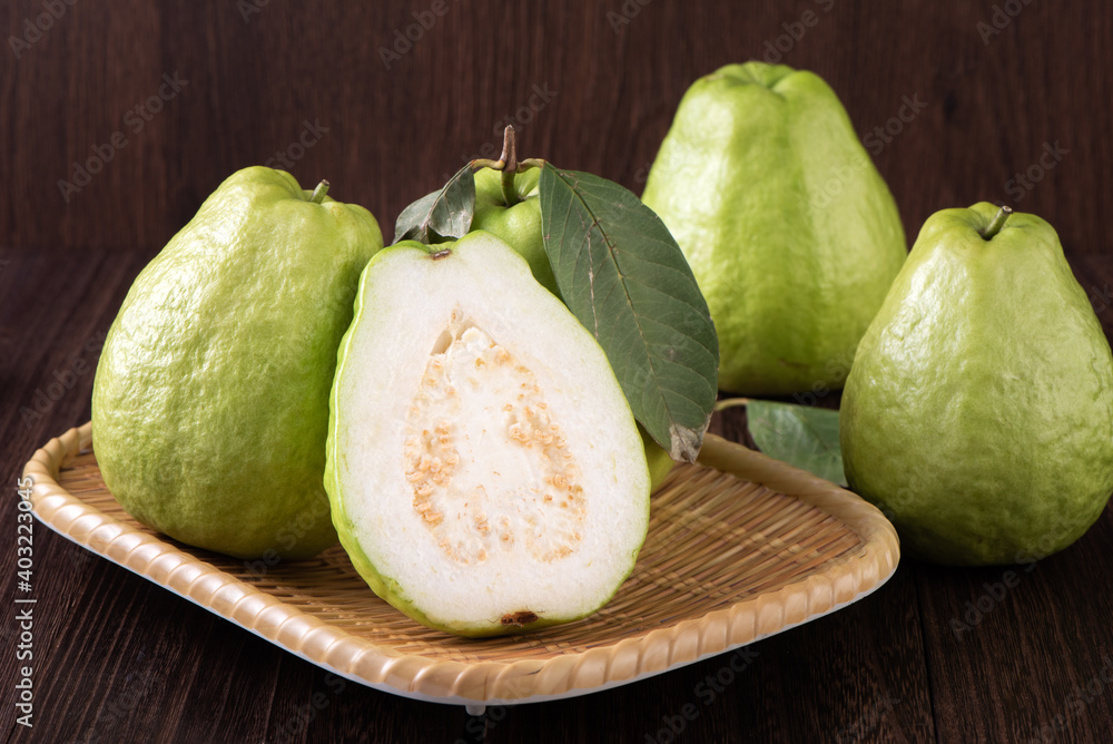 Close up of delicious guava with fresh green leaves on wooden background.