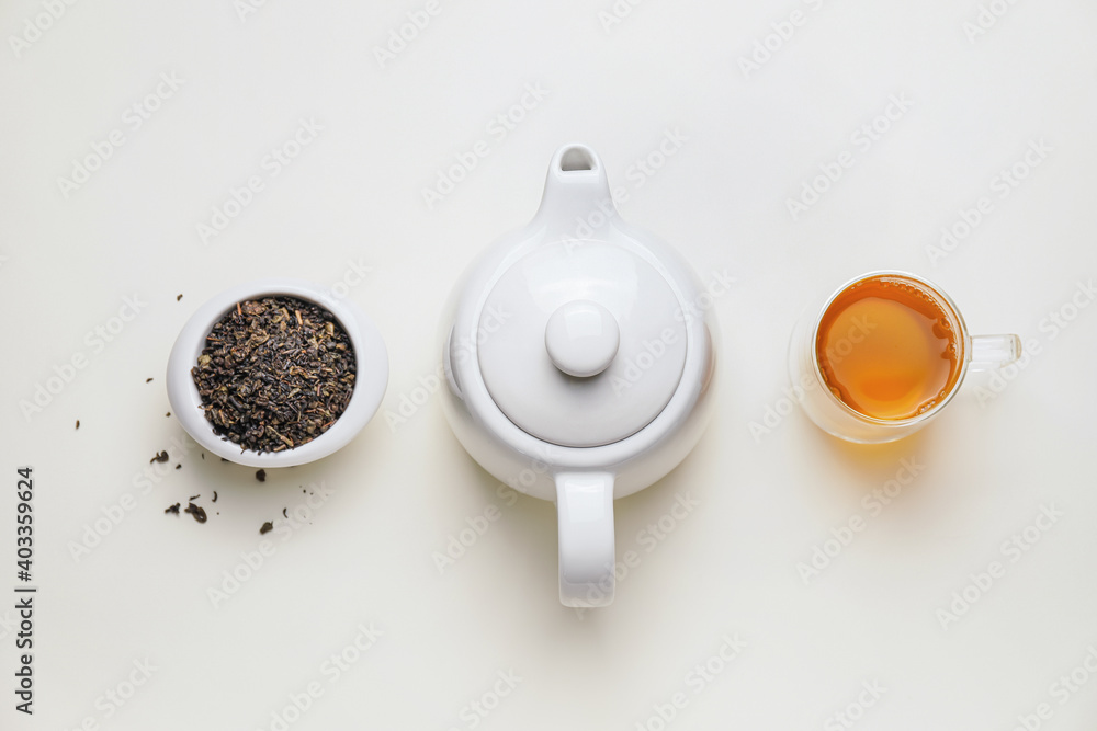 白色背景下的茶壶、一杯茶和干叶子组成