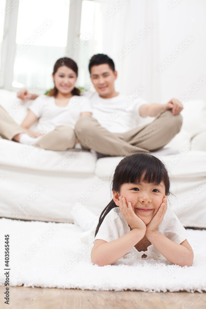 Young Chinese girl in a living room with parents in the background