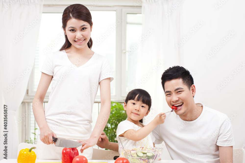 A happy family of three preparing a salad