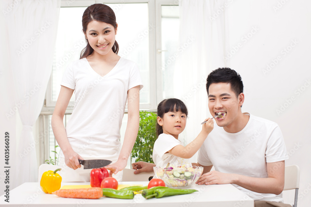 A happy family of three preparing a salad 