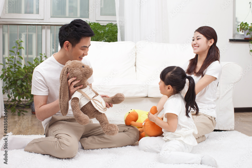 A happy family of three is playing in the living room