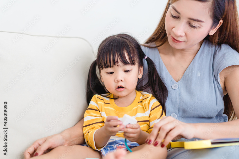 孩子和妈妈在家的沙发上。可爱的女婴在家和妈妈玩玩具。亚洲女孩，家人，Chi