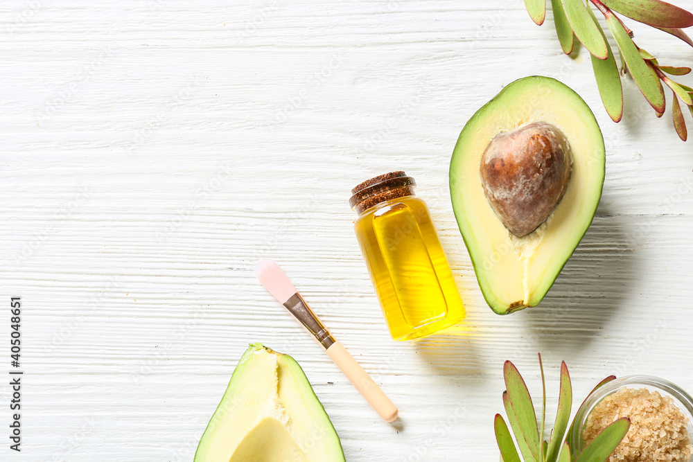 Composition with bottle of essential oil and avocado on light background