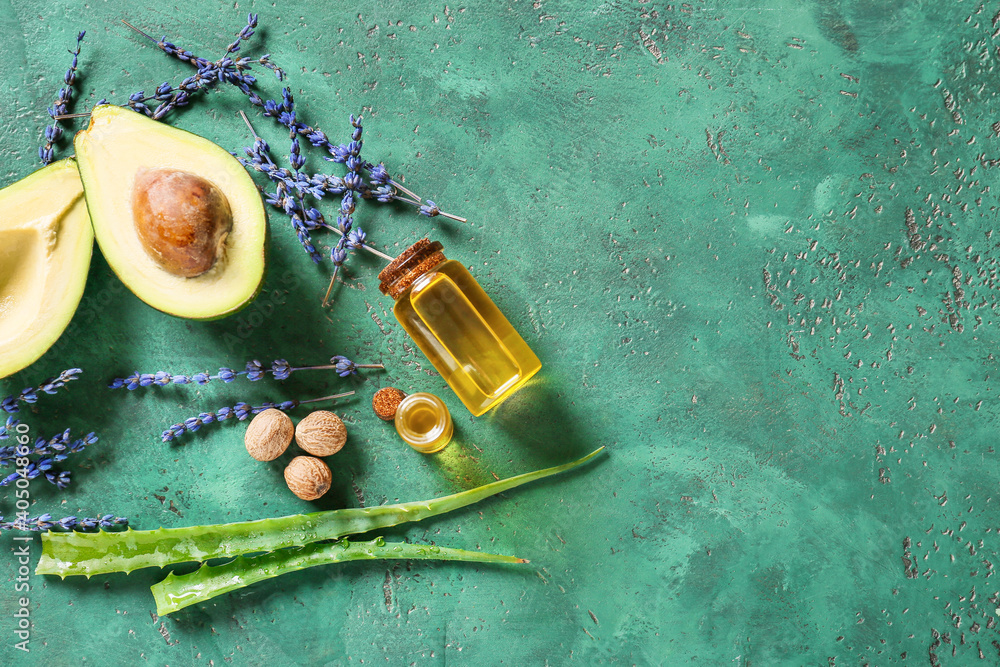 Composition with bottles of essential oil and avocado on color background