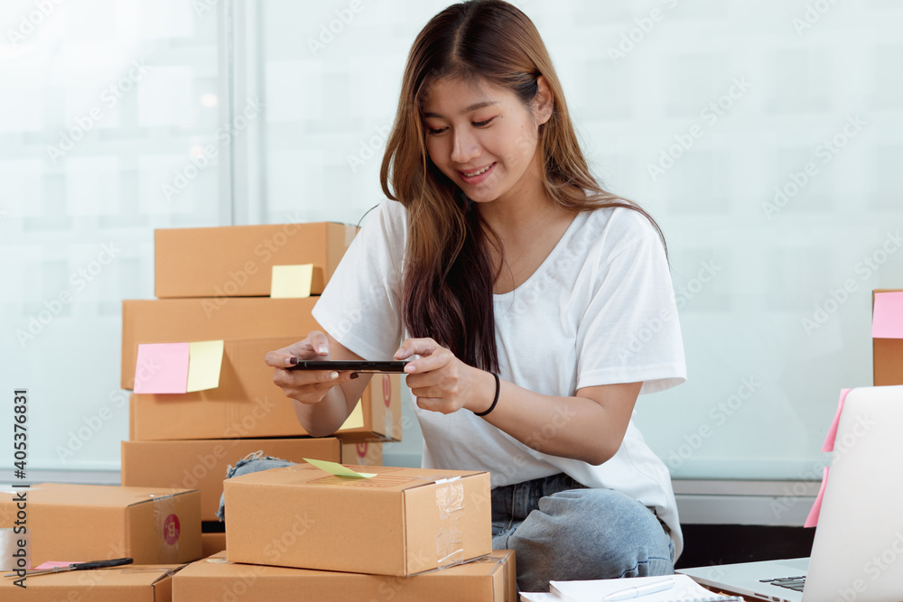 The Asian owner takes pictures of a brown package to verify his customers address and make arrangem