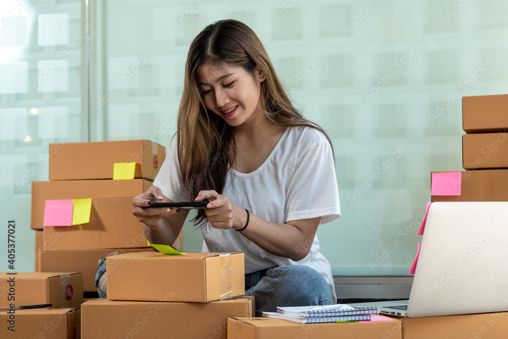 The Asian owner takes pictures of a brown package to verify his customers address and make arrangem