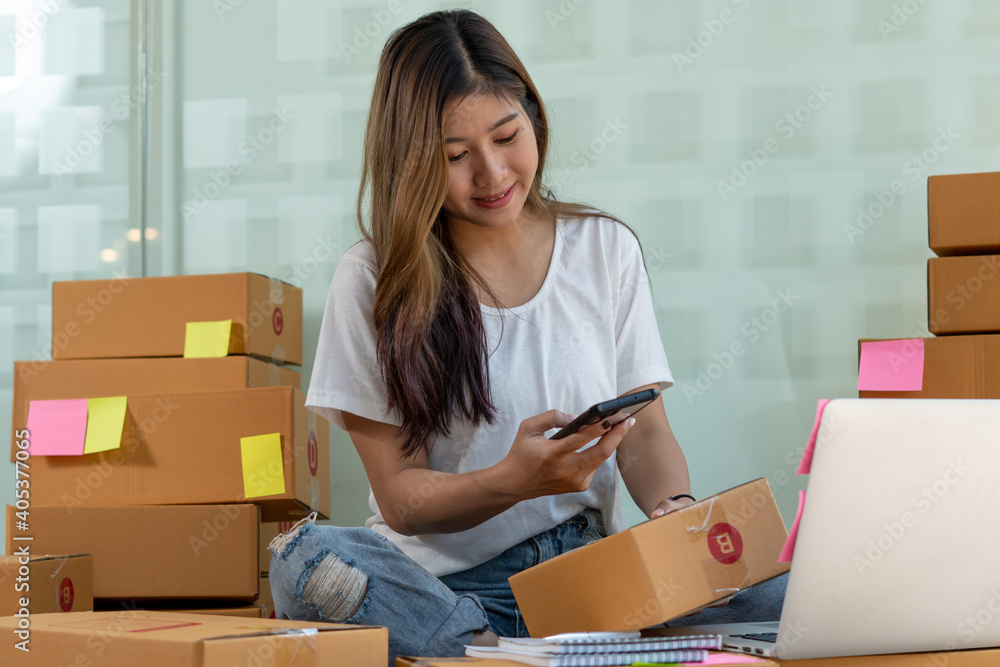 The Asian owner takes pictures of a brown package to verify his customers address and make arrangem