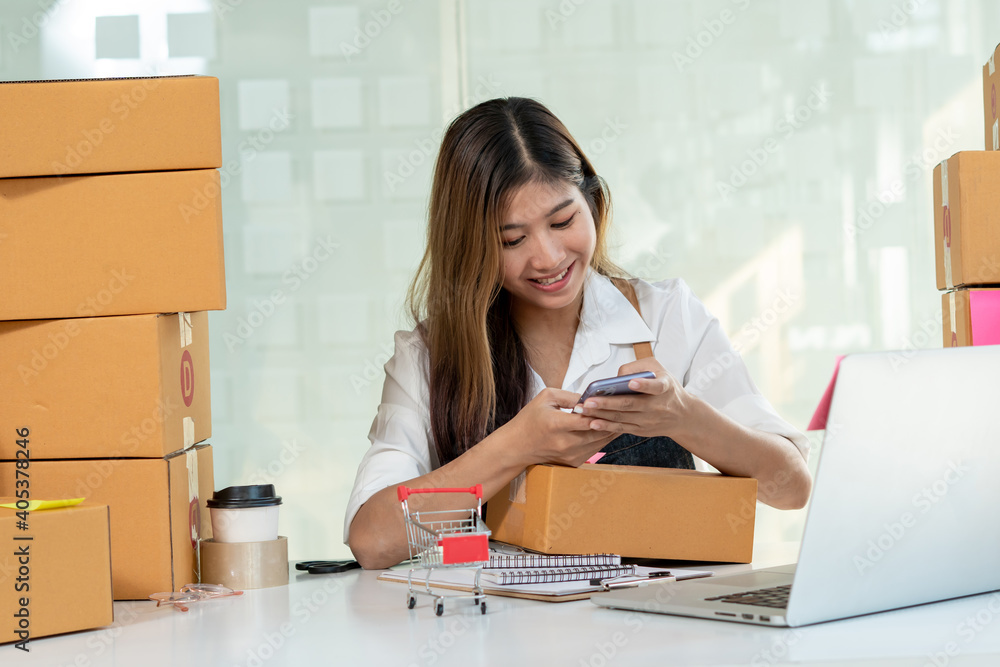 The Asian owner takes pictures of a brown package to verify his customers address and make arrangem