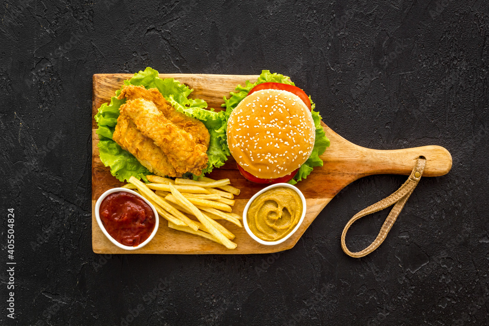 Burger with fried potatoes and chicken, top view