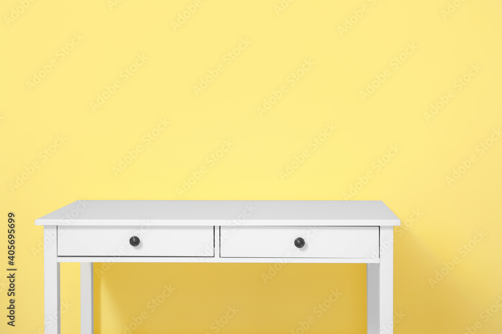 Stylish table with drawers on color background