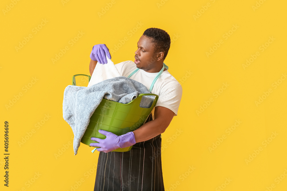 African-American man with laundry on color background