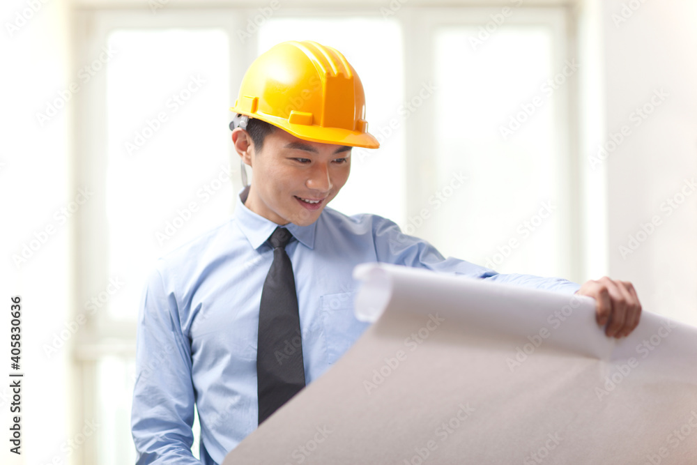 Portrait of young engineer holding blueprint in office