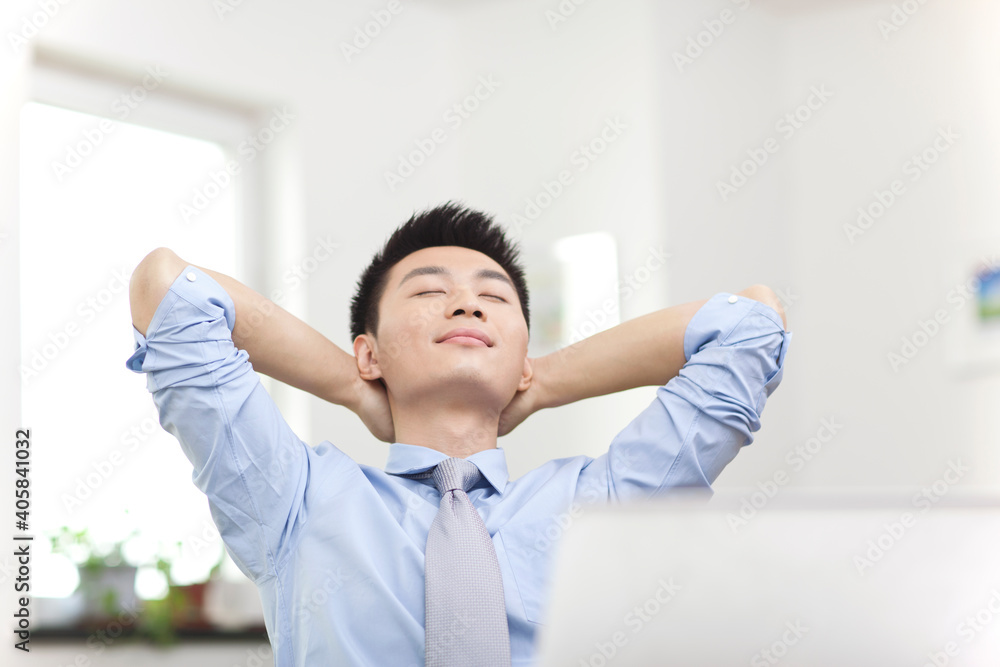 Portrait of young businessman relaxing in front of laptop